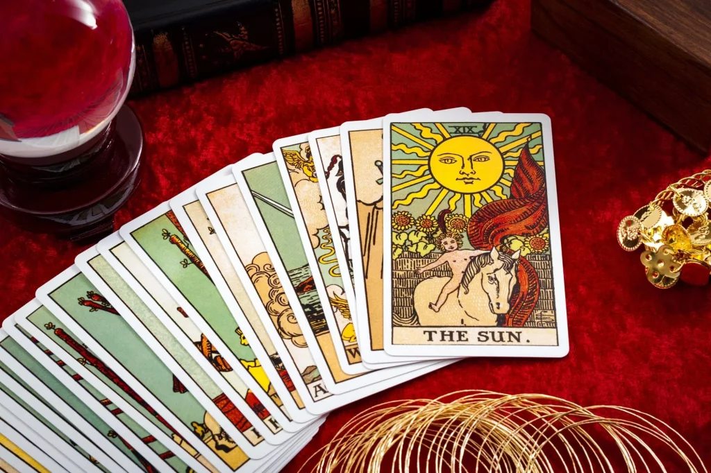 Jeu de Tarot ouvert sur une table en bois avec un carnet, pour débuter le Tarot de Marseille et le Rider-Waite